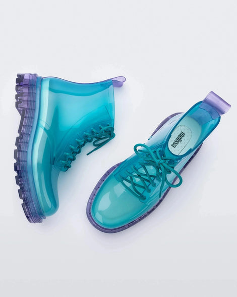 A top and side view of a pair of clear lilac/blue Melissa Coturno boots with a transparent blue base, laces and a lilac sole.