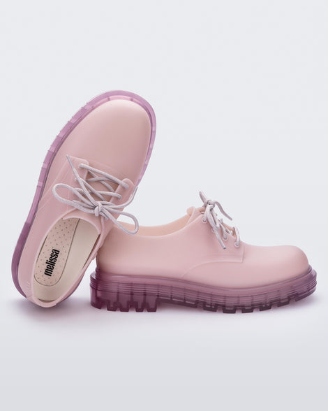 A front and side view of a pair of matte lilac Melissa Bass sneakers, with a light matte lilac base, lilac laces and a darker transparent lilac sole, leaning on eachother.