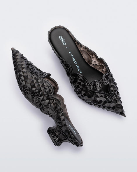 A top and side view of a pair of clear black Melissa Court heels with a heart detail on the front and a checkered pattern texture.