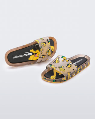 An angled front and top vew of a pair of clear beige / yellow Mini Melissa Beach slides with a beige base and a pattern of Disney's Pluto the dog with different facial expressions.