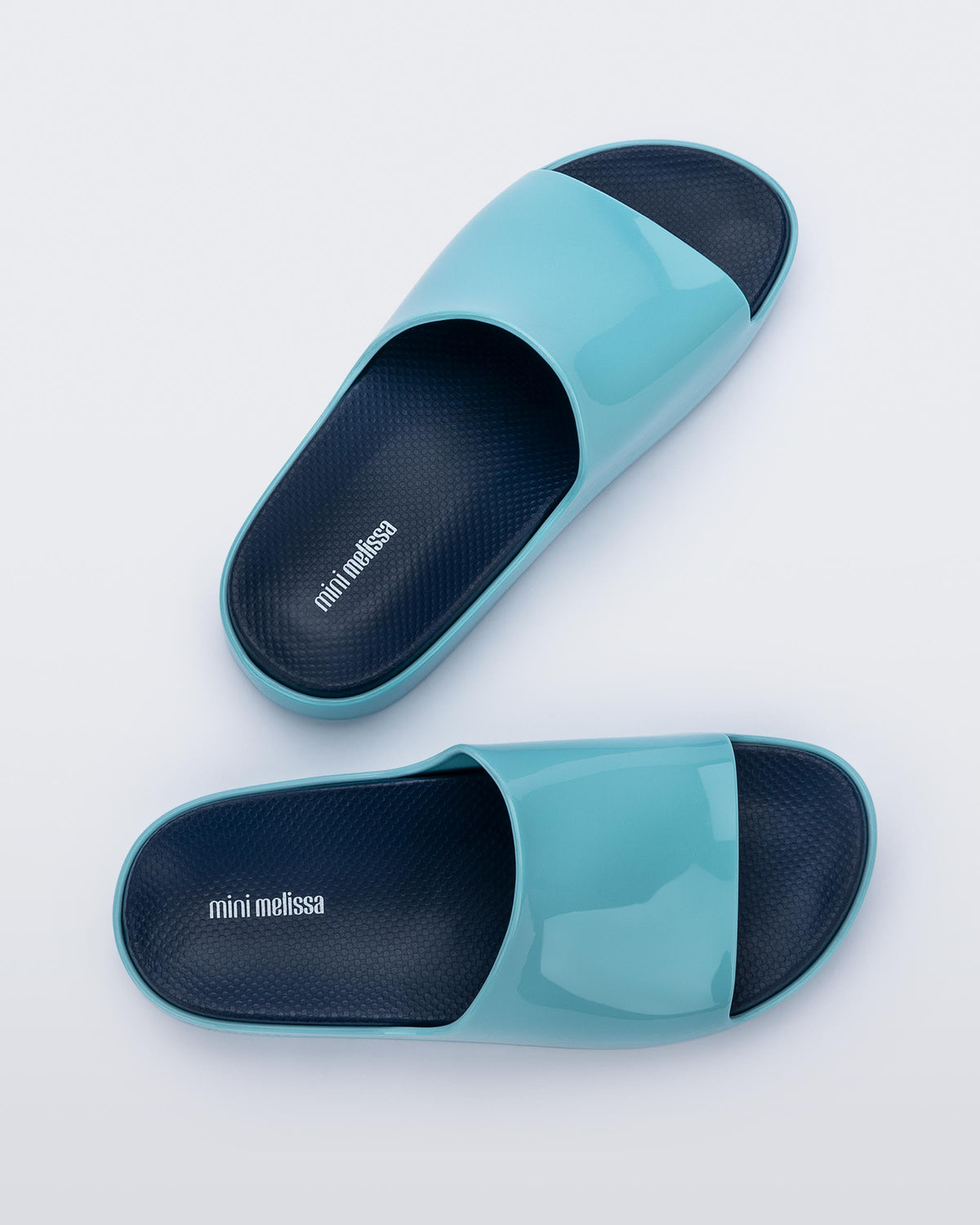 Top view of a pair of blue Mini Melissa Cloud slides with a navy blue insole and a lighter blue base.
