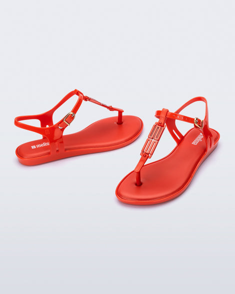 Side and front view of a pair of red Solar M Chic sandals with red embellishment