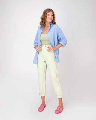 A model posing for a picture in a blue shirt and white pants wearing a pair of transparent neon pink Melissa Bikini Sandals with two transparent pink straps conjoining in the middle and a pink insole.