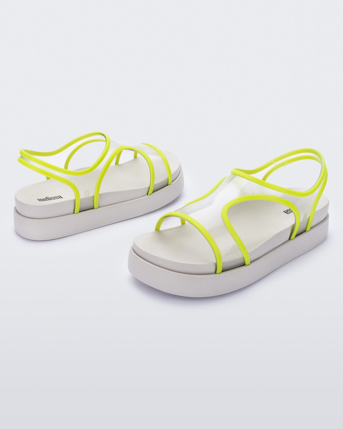 An angled front and side view of a pair of beige/green Melissa Bikini platform sandals with two transparent green straps conjoining in the middle and a beige sole.