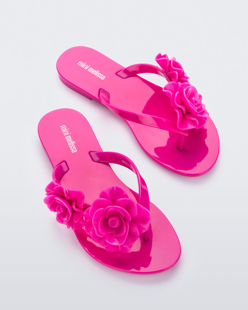 Top view of a pair of pink Melissa Harmomic Squared Garden flip flops with flowers on the straps.