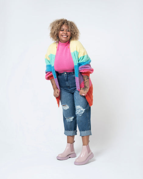 Model posing in jeans and a pink sweater wearing a pair of Melissa Step slip on ankle boots in Lilac with lug sole. 