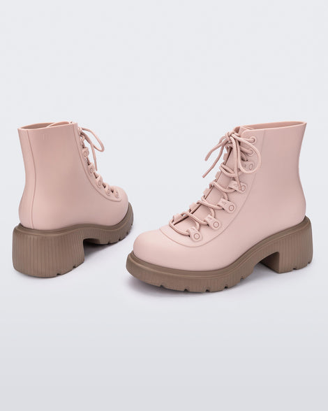 An angled back and side view of a pair of brown/pink Melissa Cosmo boots with a pink base, laces and a brown heel sole, laying on their side.