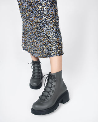 Models legs wearing a pair of green/black Melissa Cosmo boots.