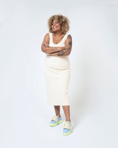 A model posing and wearing a pair of blue Melissa Buckle Up Kick Off platform sneaker with green platform sole and a yellow buckle and ivory strap.