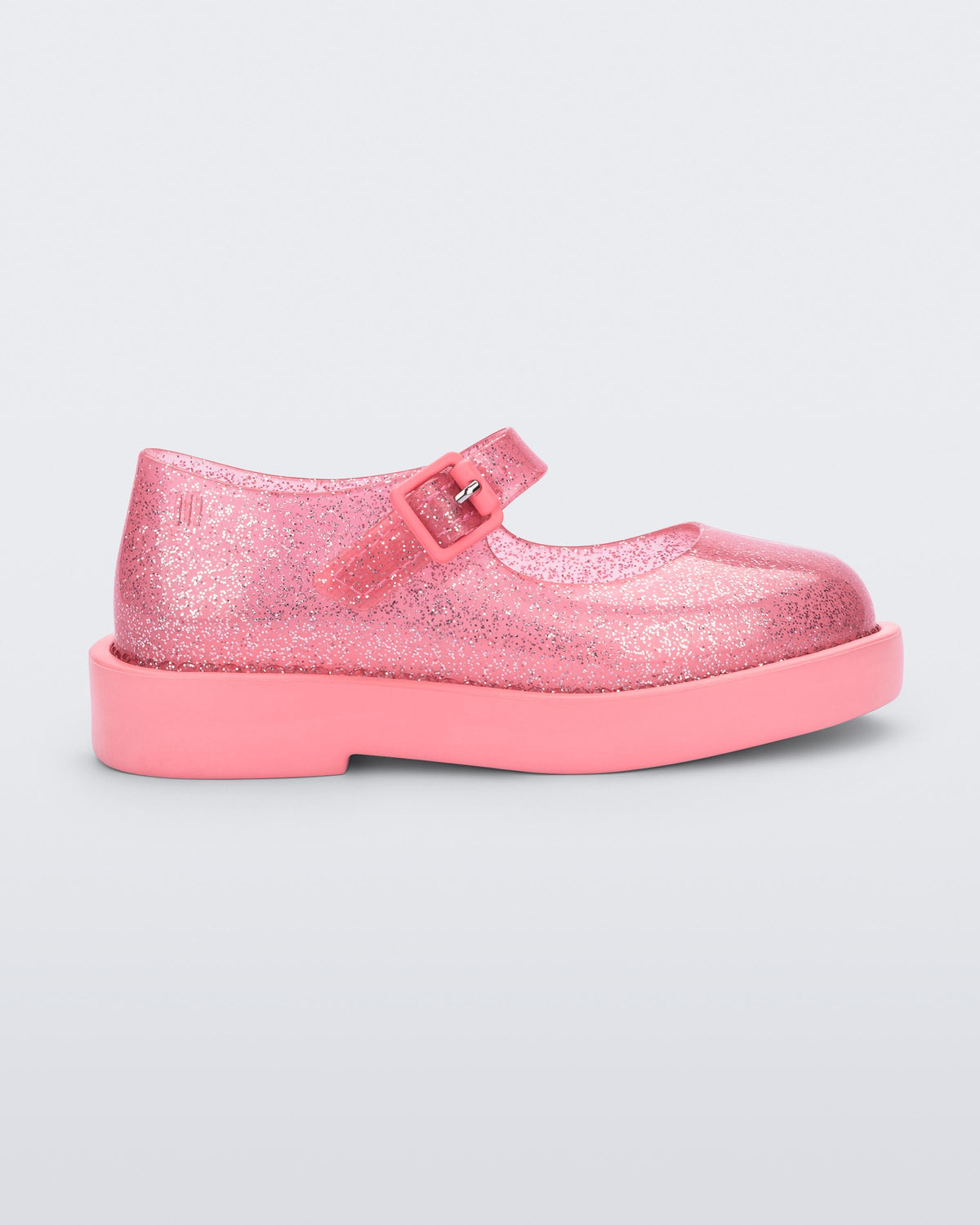 Side view of a transparent glitter pink Mini Melissa Lola loafer with a rounded toe and a pink strap and buckle.