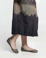 Model's legs in a dark skirt wearing a pair of glitter green Campana women's ballerina flats