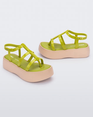 An angled front and side view of a pair of beige/green Melissa Caribe High Platform sandals with two green front straps joined by a vertical strap intersecting the ankle strap and a beige sole.