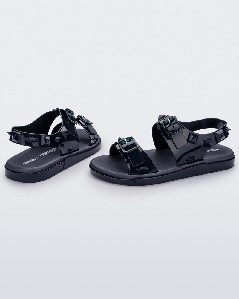 A side and back view of a pair of blue Melissa Spikes Sandals with two straps with buckles on top and spike details around the base.