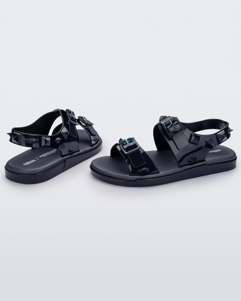A side and back view of a pair of blue Melissa Spikes Sandals with two straps with buckles on top and spike details around the base.