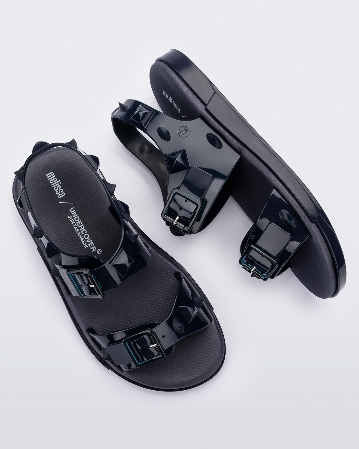 A top and side view of a pair of blue Melissa Spikes Sandals with two straps with buckles on top and spike details around the base.