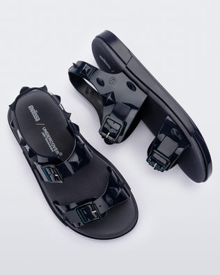 A top and side view of a pair of blue Melissa Spikes Sandals with two straps with buckles on top and spike details around the base.