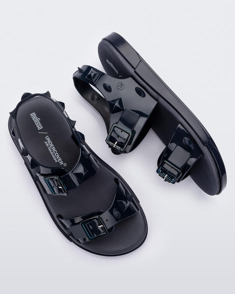 A top and side view of a pair of blue Melissa Spikes Sandals with two straps with buckles on top and spike details around the base.