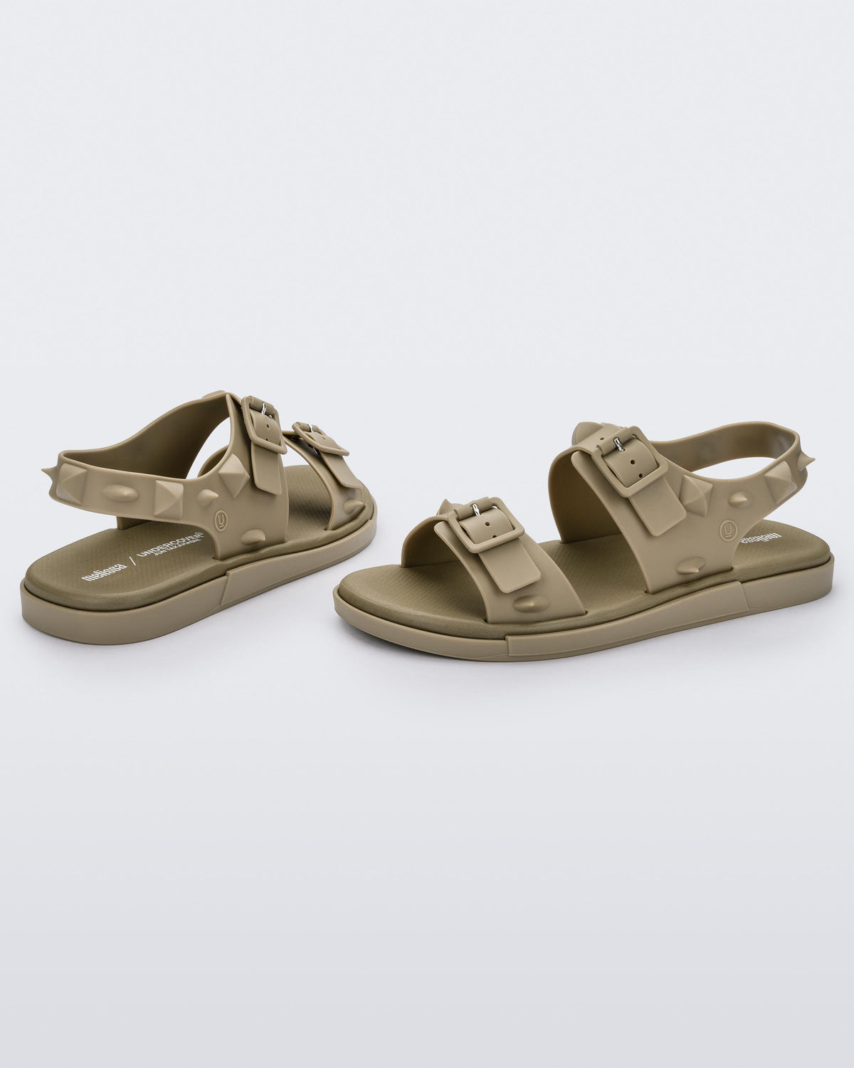 A side and back view of a pair of beige Melissa Spikes Sandals with two straps with buckles on top and spike details around the base.