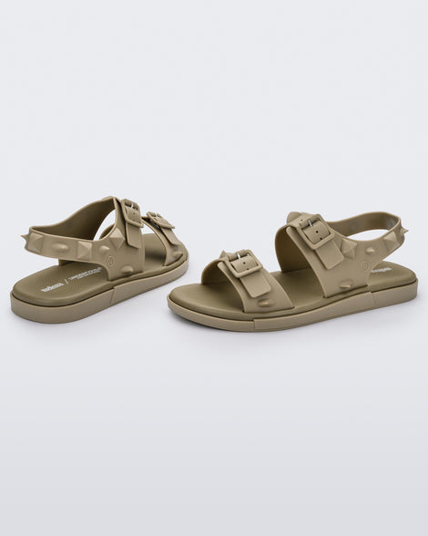 A side and back view of a pair of beige Melissa Spikes Sandals with two straps with buckles on top and spike details around the base.