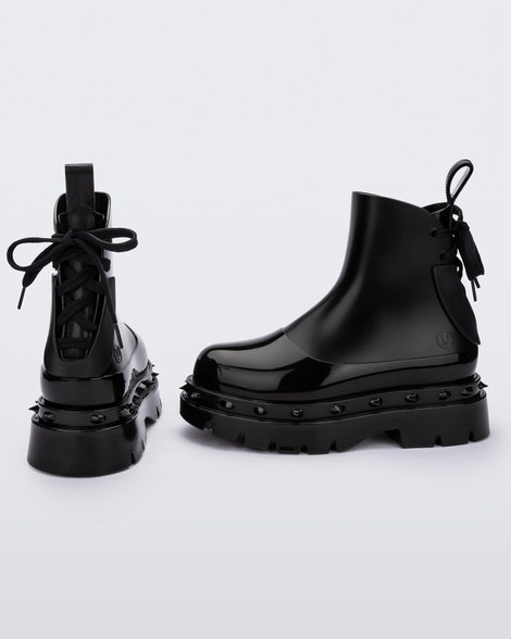 A side and back view of a pair of black Melissa Spikes Boots with spike details around the sole and laces in the back.
