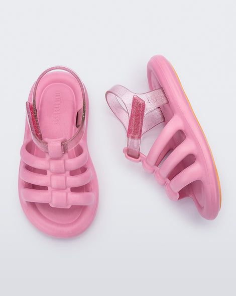 Top and side view of a pair of pink Mini Melissa Freesherman sandals pink and clear glitter straps.