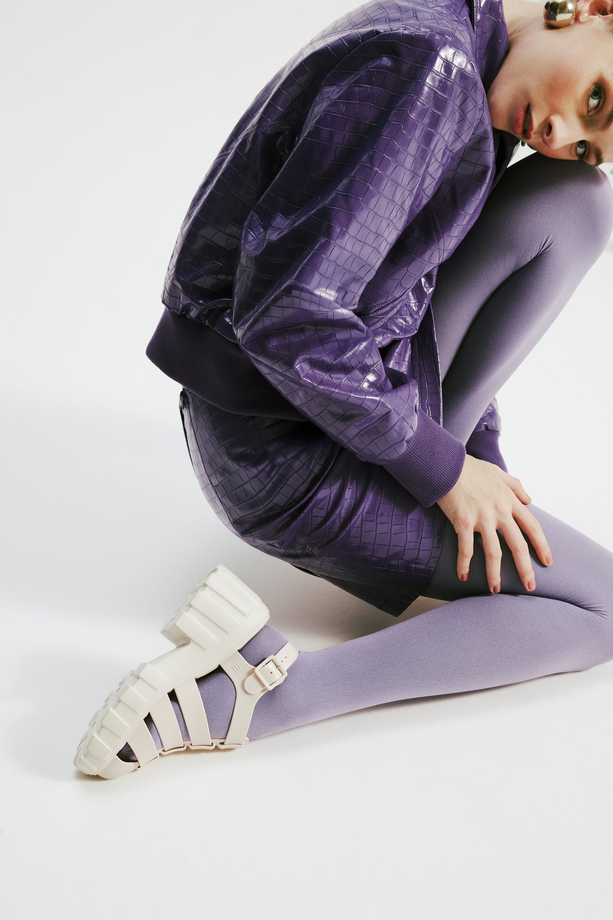 Model sitting down in a purple dress with purple tights wearing a pair of beige Megan platform sandals