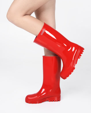 Models legs wearing a green of red Melissa Welly boots.