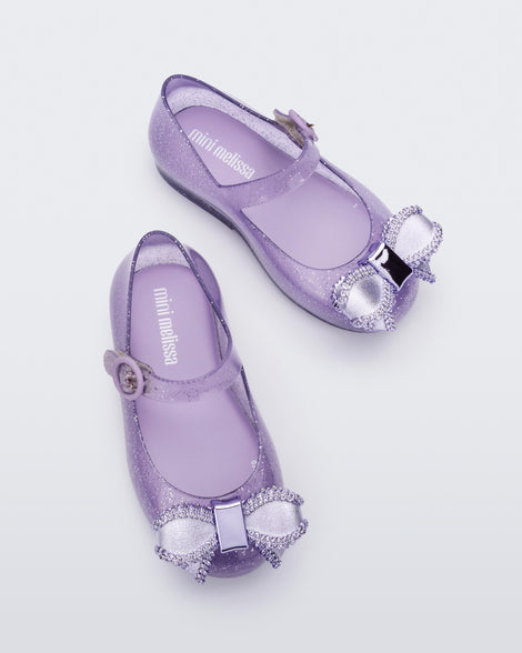 Top view of a pair of lilac Mini Melissa Sweet Love baby mary jane flats with a metallic lilac bow.