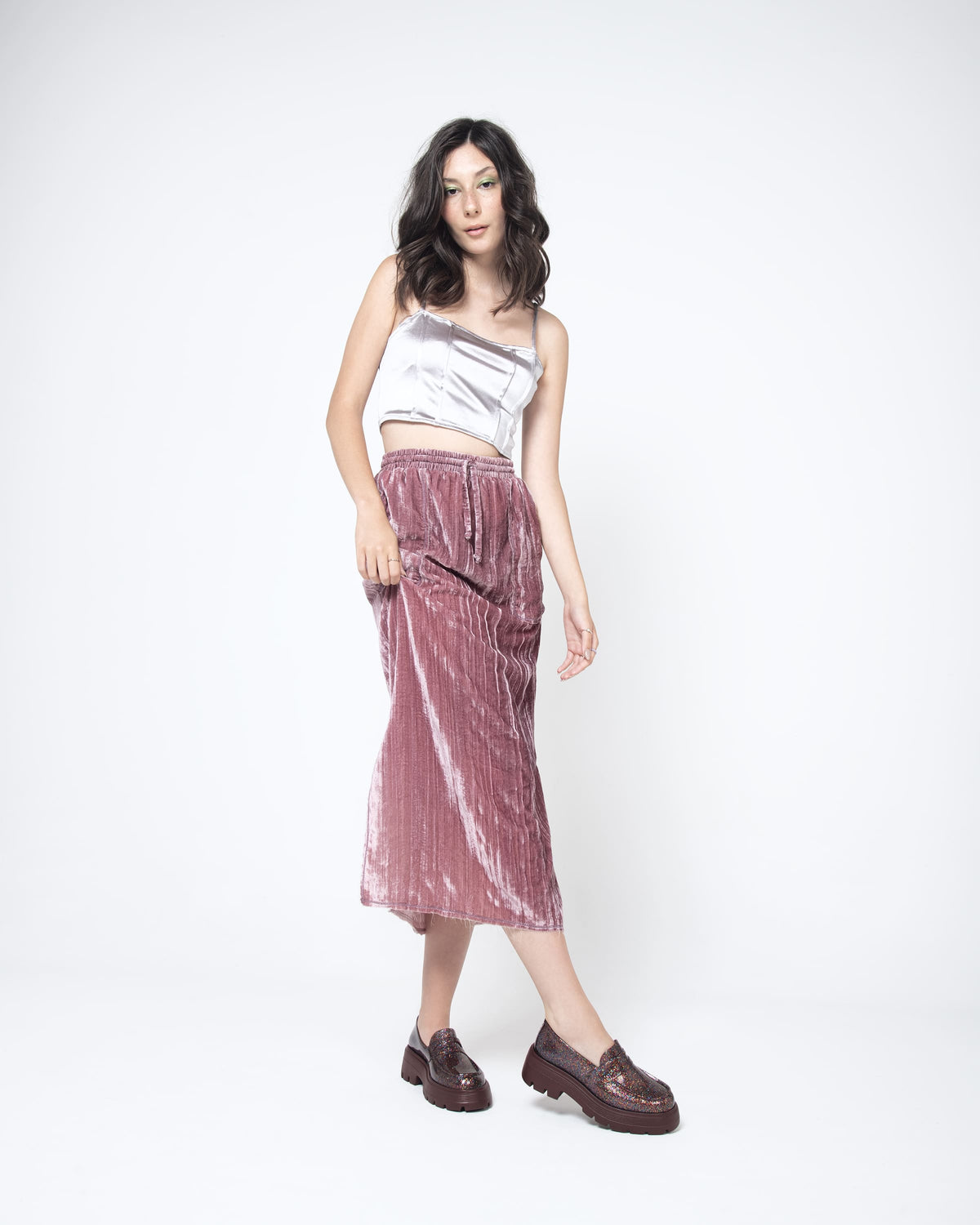 A model posing wearing a pair of  Melissa Royal loafers in glitter multicolor with a brown platform sole.