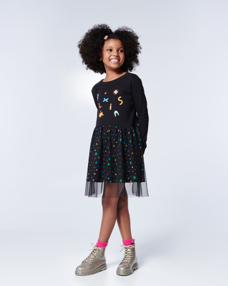 Model posing in a black and rainbow print dress wearing a pair of Mini Melissa lace up Coturno boots in gold glitter color-way paired with bright pink ankle socks.