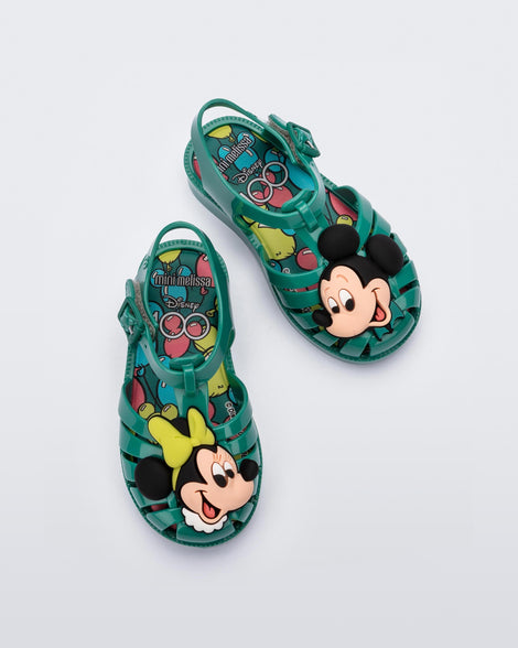 Top view of a pair of green Mini Melissa Possession + Disney 100 sandal with Mickey on one foot and Minnie on another foot.