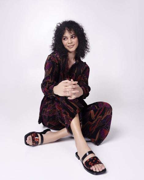 Model in a black patterened outfit wearing a pair of black and tortoise Ivy women's slide