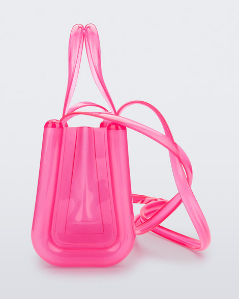 Side view of a pink small Melissa Jelly Shopper bag + Telfar bag with a handle and straps.