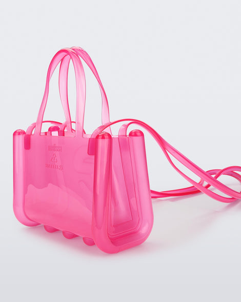 Angled view of a pink small Melissa Jelly Shopper bag + Telfar bag with a handle and straps.