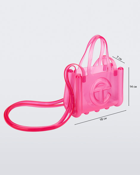 Angled view of a pink small Melissa Jelly Shopper bag + Telfar bag with a handle and straps. Dimensions 18 cm length, 7 cm width, 14 cm height