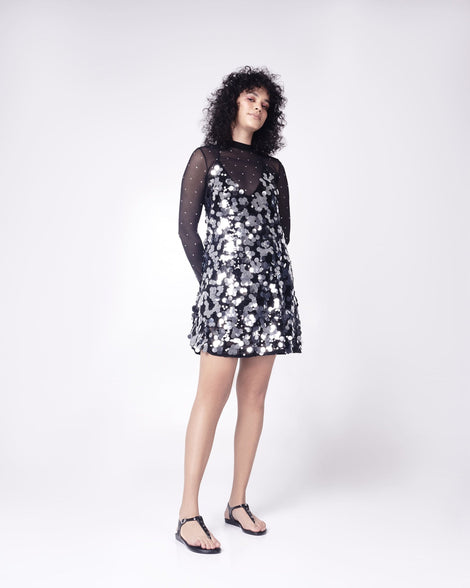 Model in a black dress wearing a pair of black Melissa Solar studs sandals with gold studded t-strap and gold buckle.