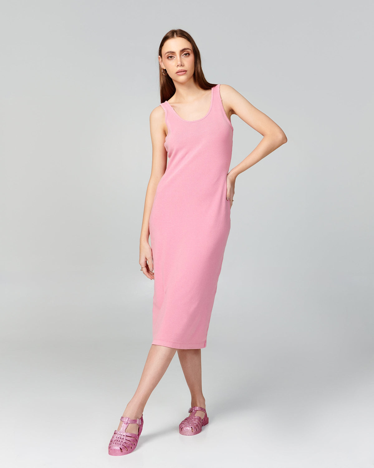 Model in a pink dress wearing a pair of glitter pink Possession sandals.