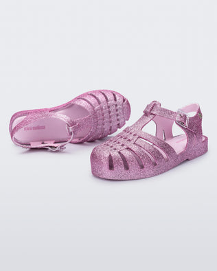 Top and side view of a pair of glitter pink kids Possession sandals.