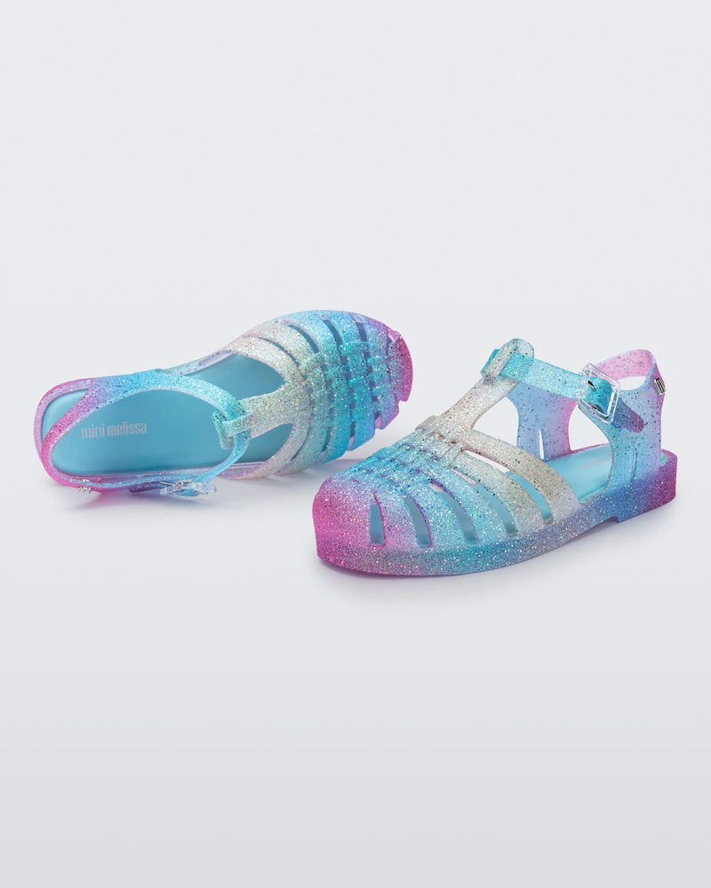 Top and side view of a pair of blue and pink glitter kids sandals Possession sandals.