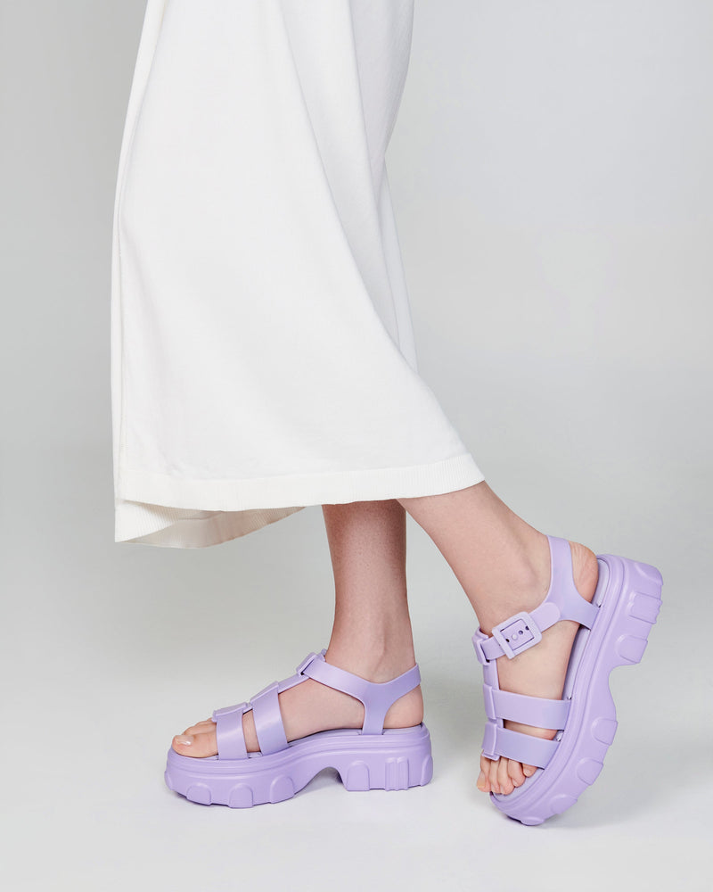 Model's legs in a white skirt wearing a pair of lilac Ella platform sandals