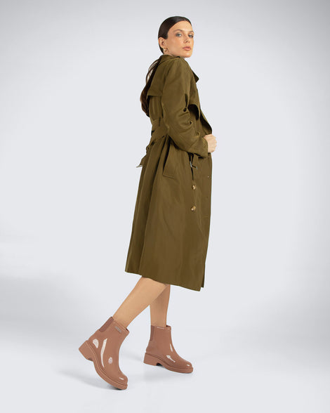 Model in a green trench coat wearing a pair of brown Chelsea Boots.