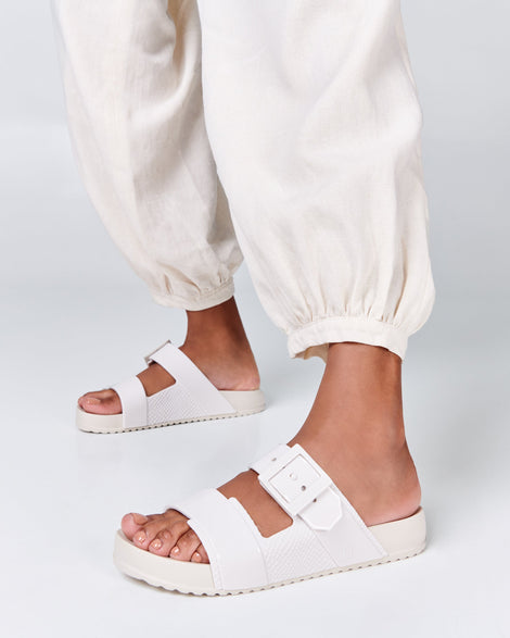 Model's legs wearing a pair of white Cozy Connection slides