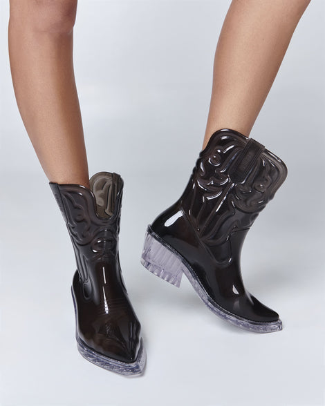 Model's legs wearing a pair of transparent black Texas boots