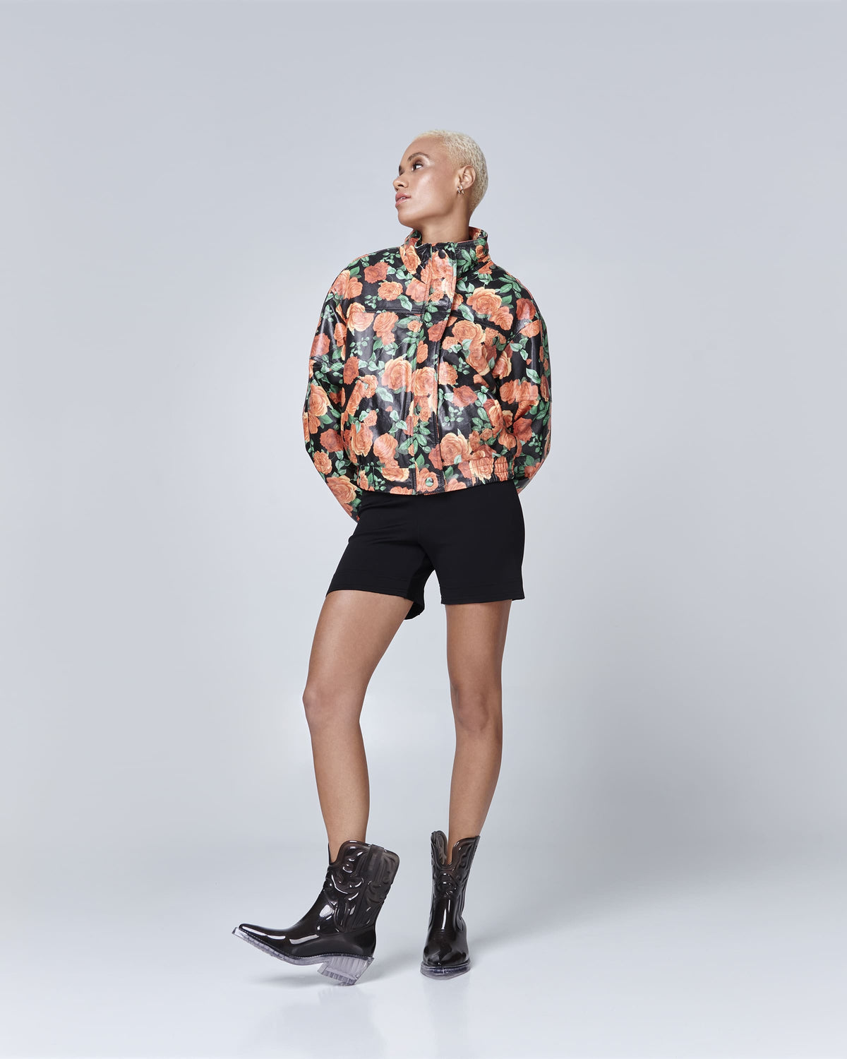 Model in black shorts and orange flower jacket wearing a pair of transparent black Texas boots