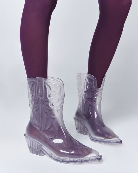 Model's legs in plum colored tights wearing a pair of clear Texas boots.