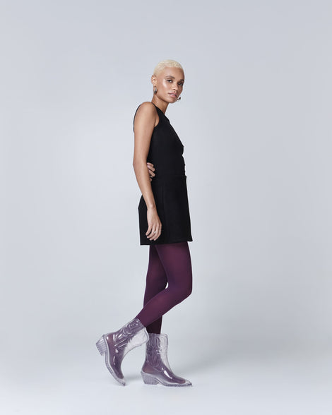 Model in a black dress and plum colored tights wearing a pair of clear Texas Boots