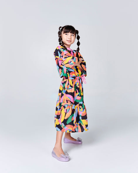Child model in a multi color dress wearing a pair of purple Sweet Love Butterfly kids flats.
