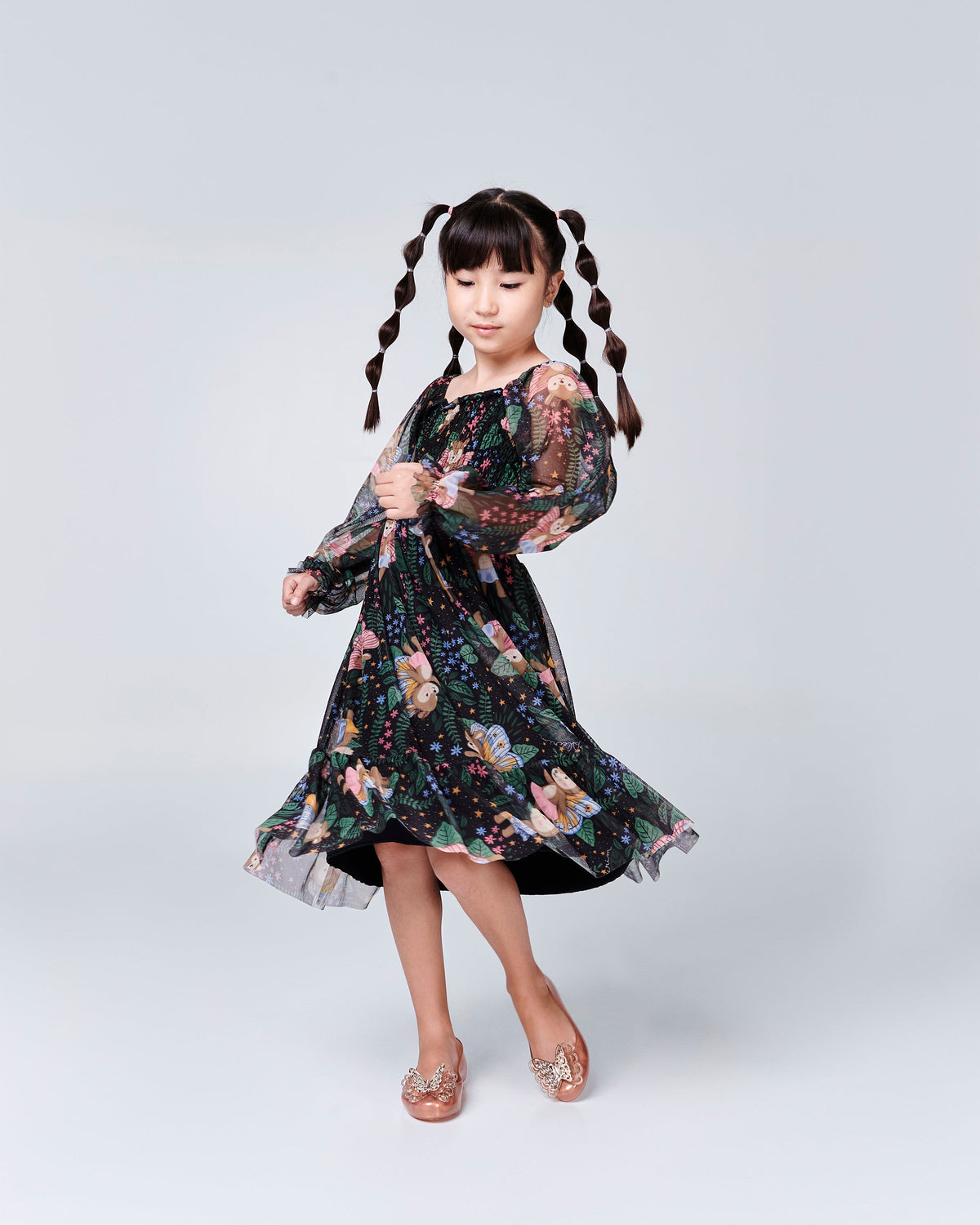 Child model in a black floral dress wearing a pair of gold Sweet Love Butterfly kids flats
