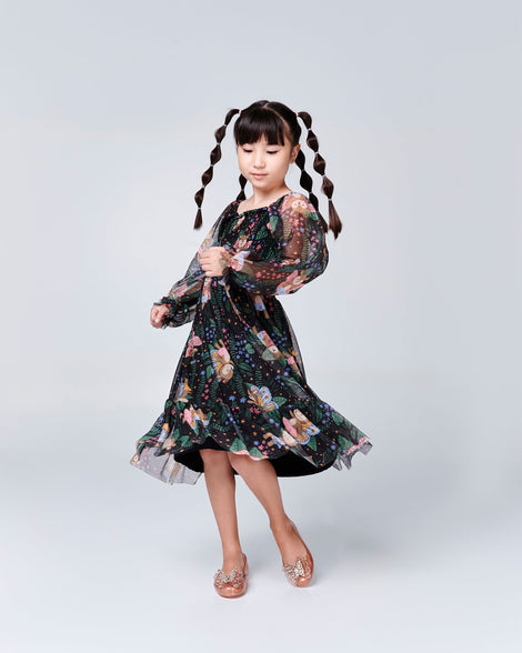 Child model in a black floral dress wearing a pair of gold Sweet Love Butterfly kids flats