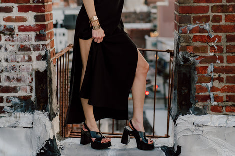 Model's body in a black dress in a city landscape wearing a pair of black Dance Heels